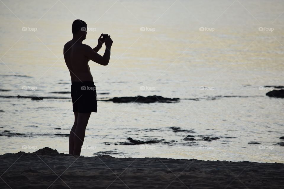 silhouette of man taking photos of sunset over St Kilda Beach Melbourne Australia