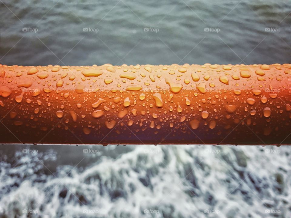 Water drops on orange metal bar