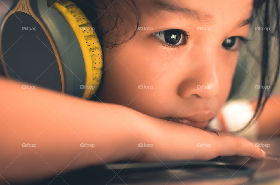 A girl on headphones watching a movie on her device.