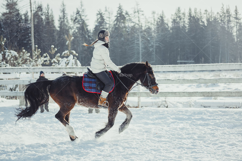 Teenage girl horseback jumping at cold winter day