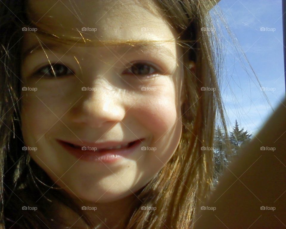 A little girl smiles at the camera on a sunny day in rural America