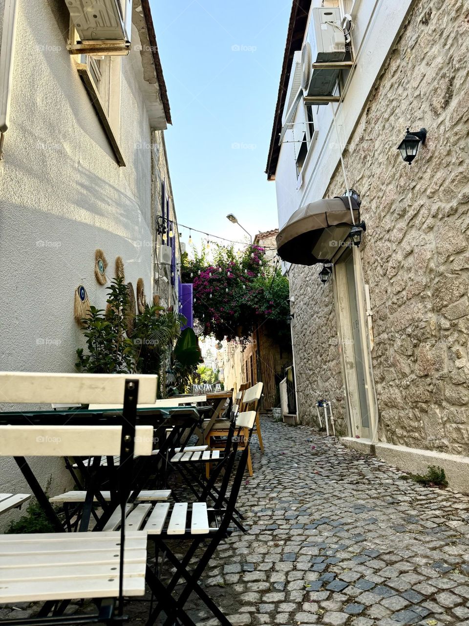 A narrow stone street with tables and chairs arranged to create a cozy atmosphere for relaxation.