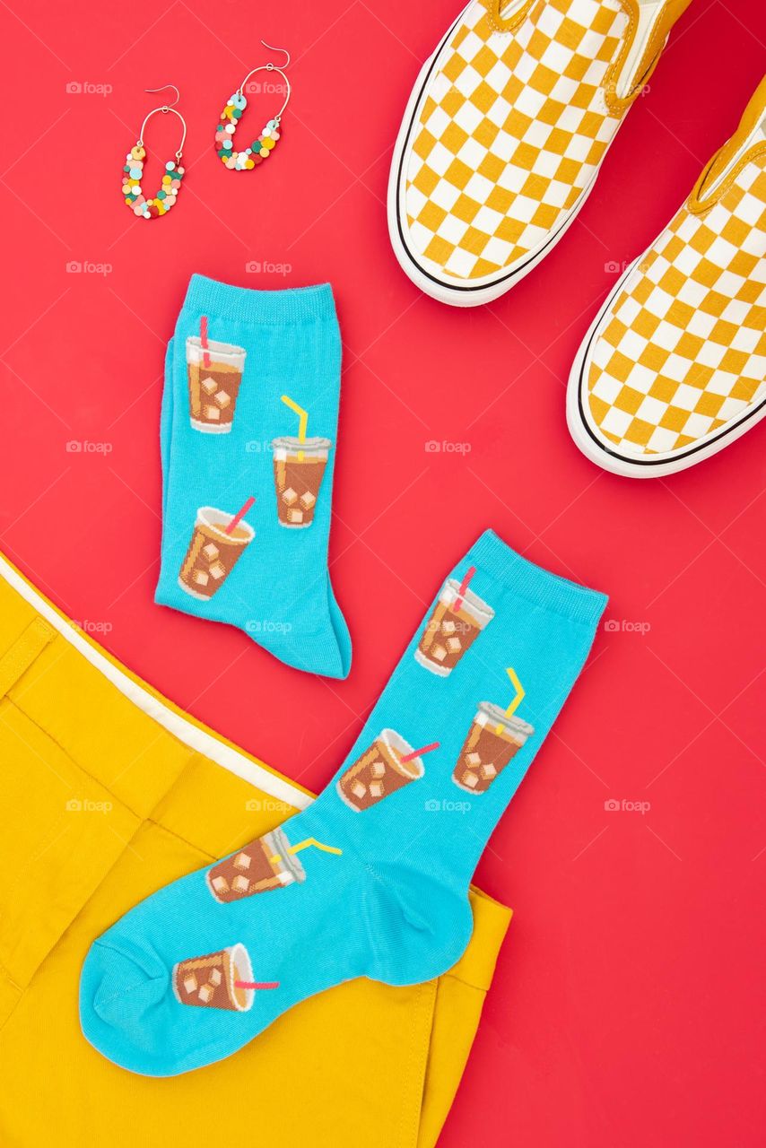 Bright and colorful flat lay of yellow shorts, shoes, socks and earrings 