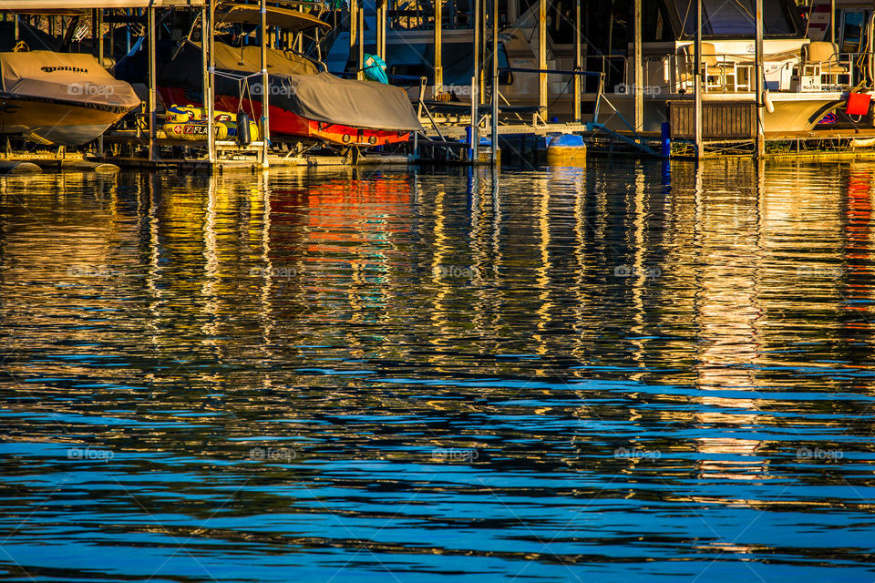 Reflections of colorful boats creating abstract colors in the rippled surface of a the water at sunrise