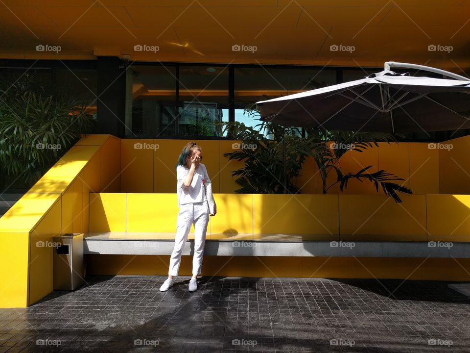 A girl in white outfit next to a yellow wall