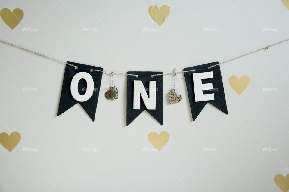 Black pennant banner on a twine string that reads ONE for a first birthday with hearts