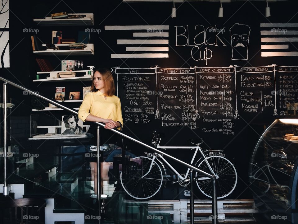 Pretty woman standing on staircase at cafe