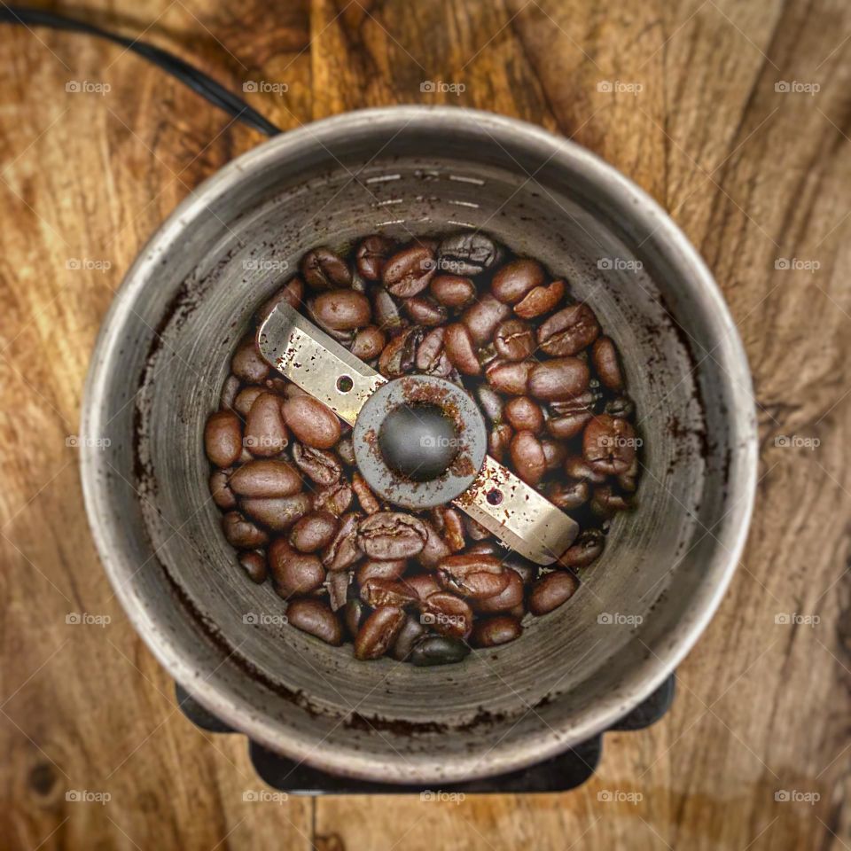 Coffee beans in an electric grinder on a wooden table
