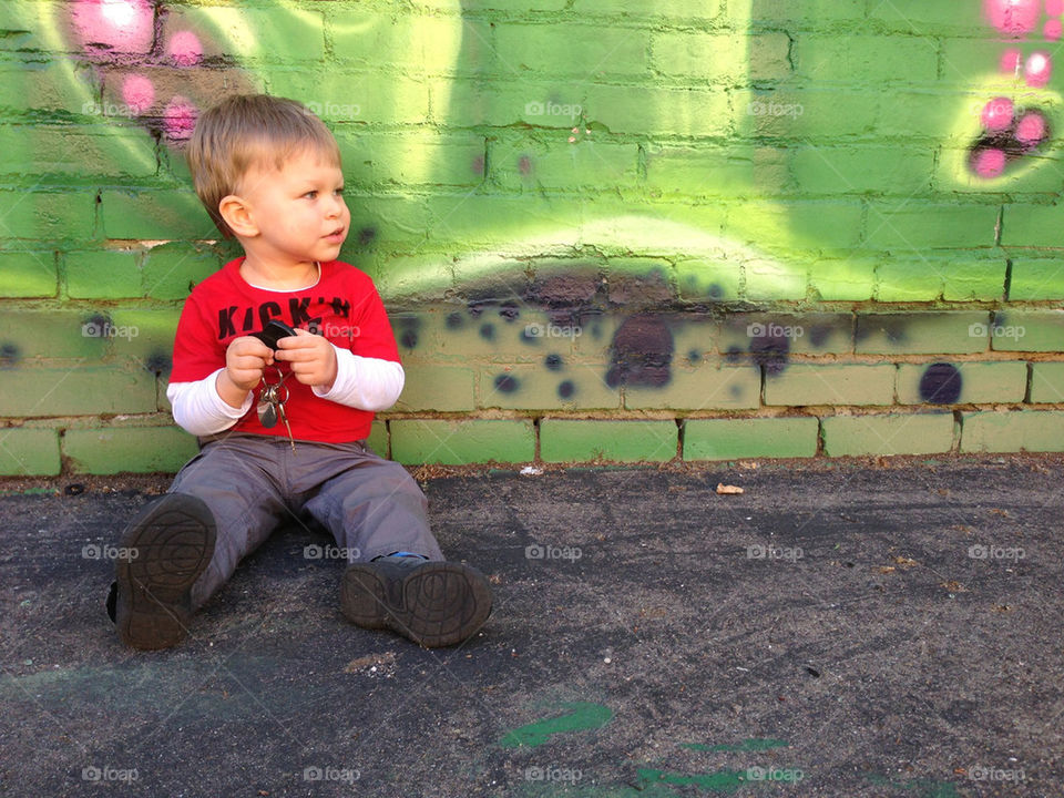 Toddler playing with car keys on ground by wall 