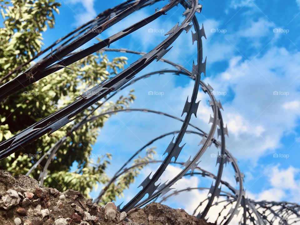 Barbed wire on top of the prison wall against blue sky 