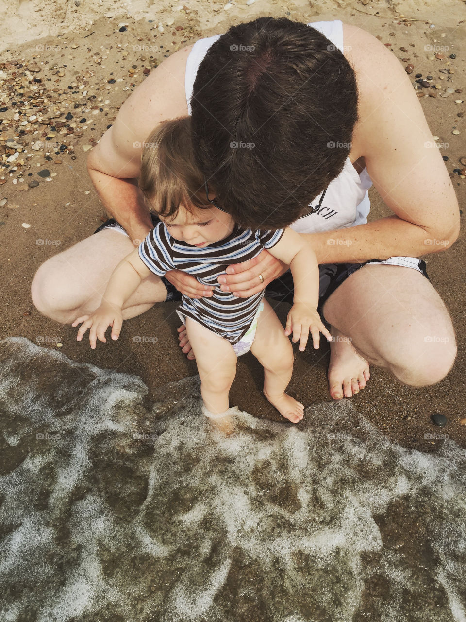 Man carrying her baby on coast at beach