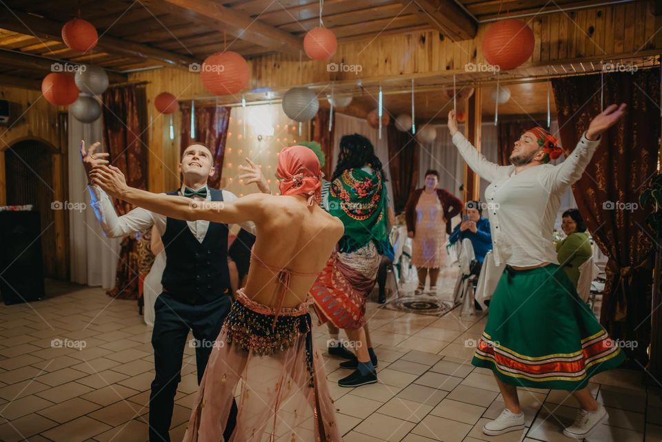 photo of a moment from a wedding where the groom dances with his friends dressed as women