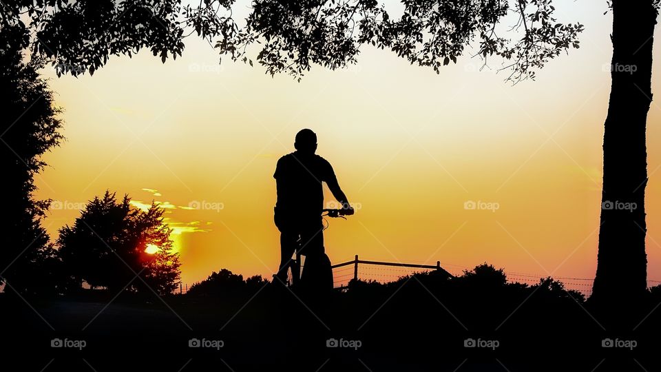 Man riding his bike at sunset in silhouette