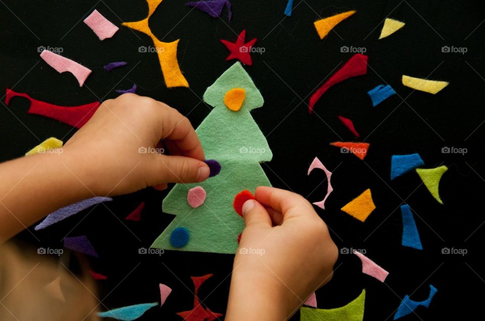 Children's hands decorate a felt handmade Christmas tree. Christmas flat lay. Top view. Christmas background 