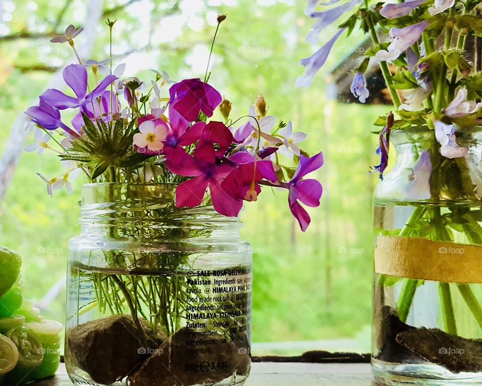 Fresh wildflowers in glass jars brighten up a kitchen window sill 