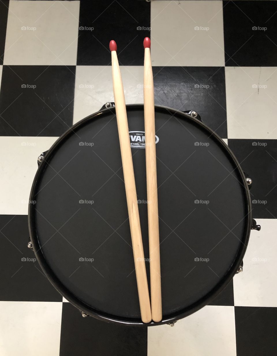 Black drum and drum sticks with checkerboard floor 