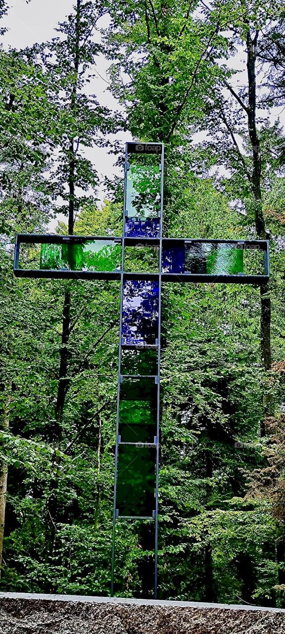 This artful creation, a large cross made from metal and green tinted glass was seen at the “Bayerische Landesgartenschau”, the “Bavarian State Garden Show”. in “Freyung”, Germany. 2023. Hypnotic Productions
