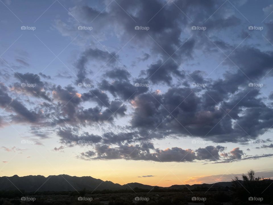 A colorful sunset with clouds and mountains. 