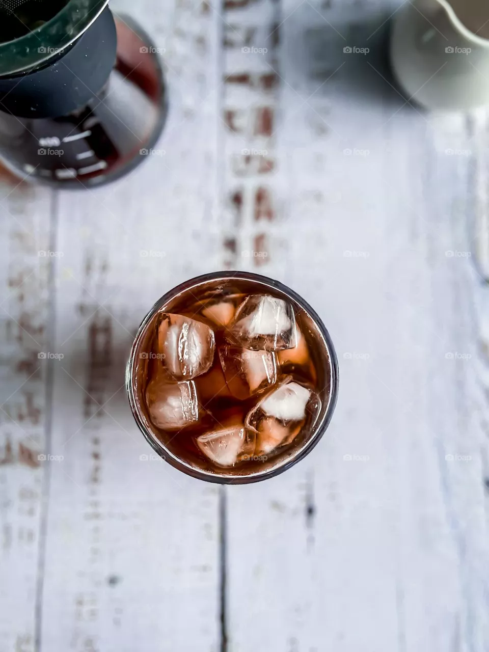 Iced Americano in a cup full with ice on a white wooden table