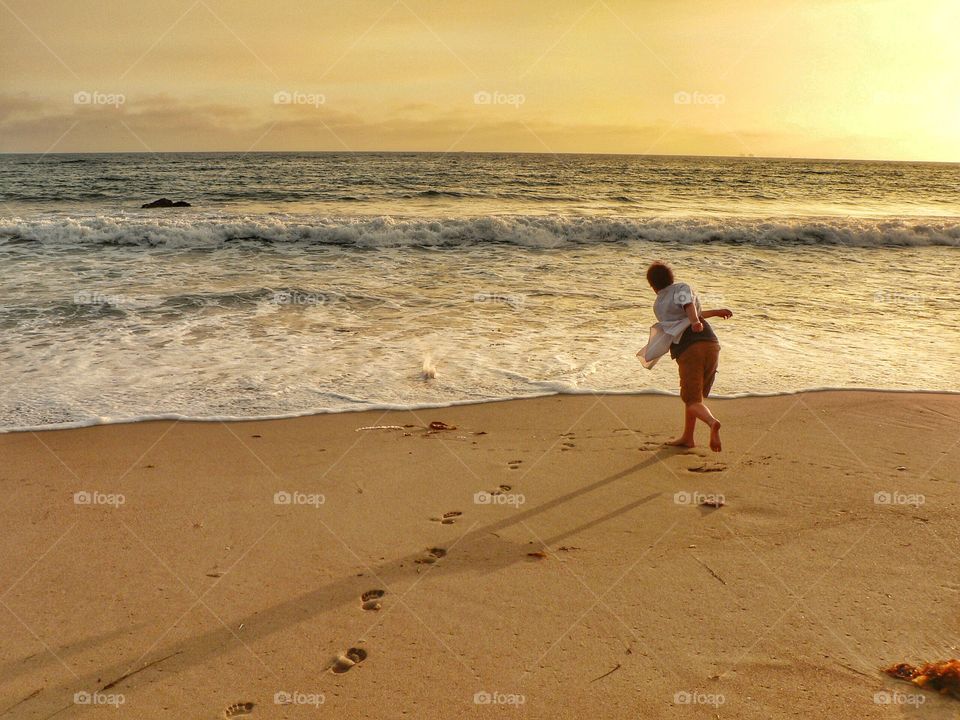 A boy skipping rocks into the ocean 