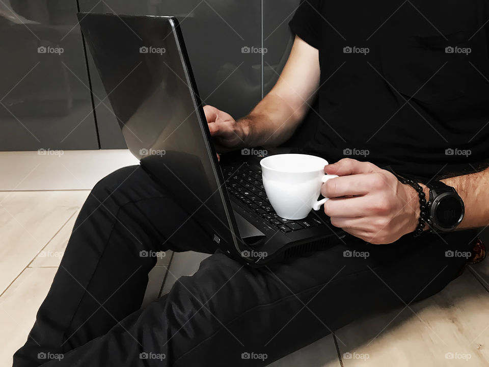 Young man drinking coffee while using laptop in the morning 