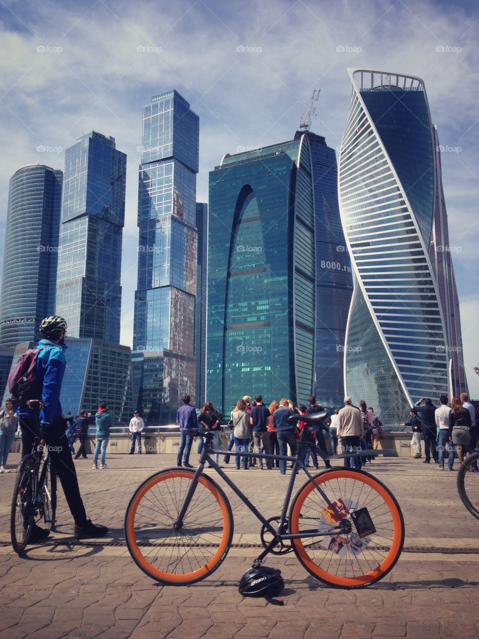 Grey brakeless fixie bike with orange wheels in front of Moscow skyscrapers city centre, Russia