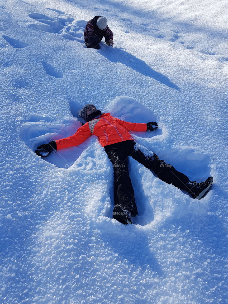 kid making a snow angel in winter clothes