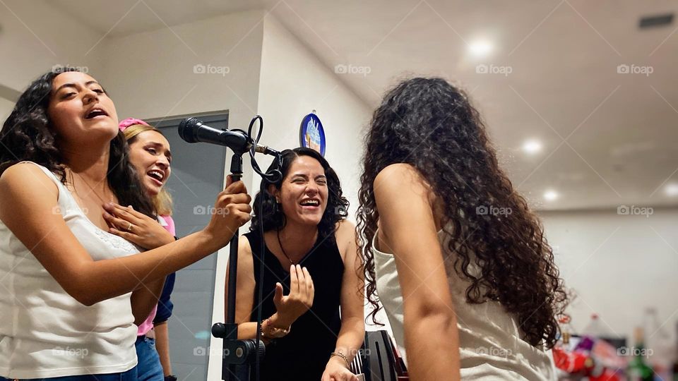 Group of women singing an emotional song, while laughing and enjoy the karaoke, at the midnight.