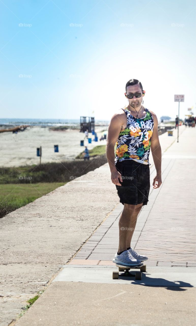 Male skateboarding along beach