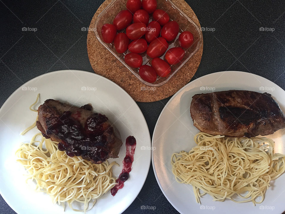 Plates with fried duck fillet under sweet berry sauce and pasta