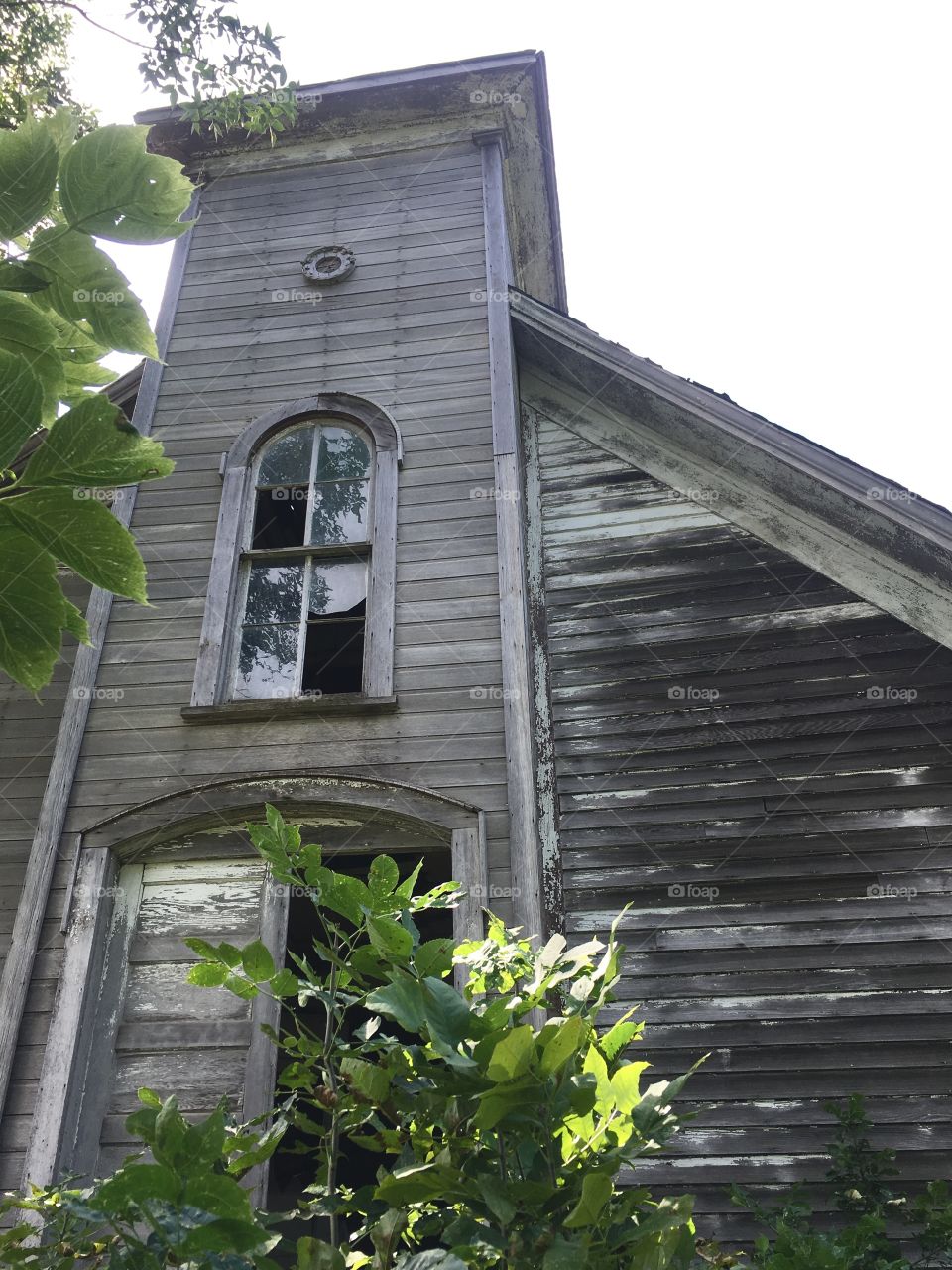 Abandoned church with paining peeled of that has graying wood & broken windows. Found in a small town in midwestern America.