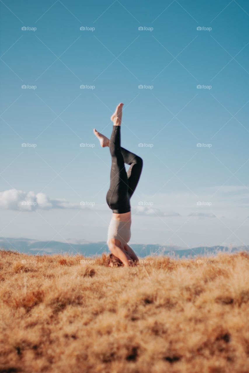 woman doing  a headstand on top of the mountains