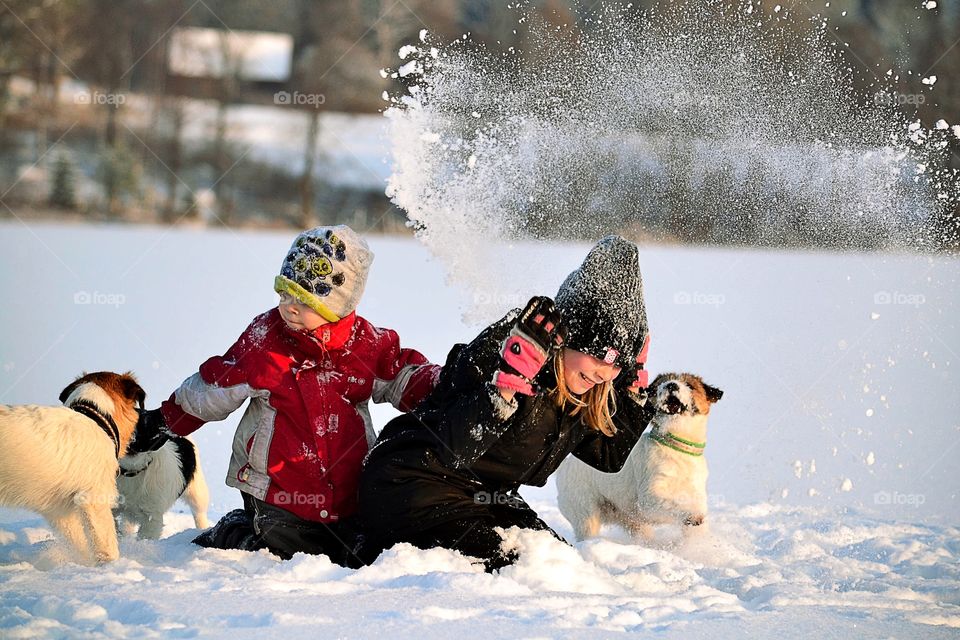 Brother and sister enjoying with dogs in snow