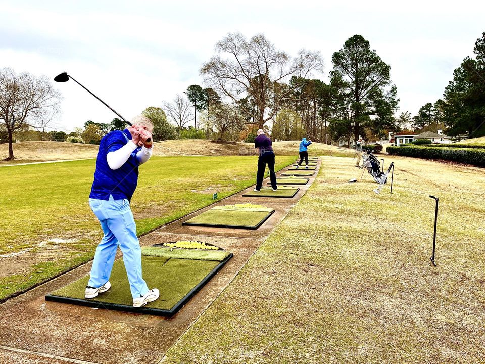 Getting ready for the golf season by practicing swings at the driving range 