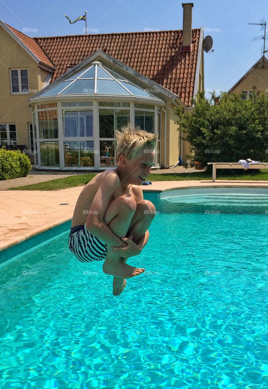 Shirtless boy jumping to swimming pool