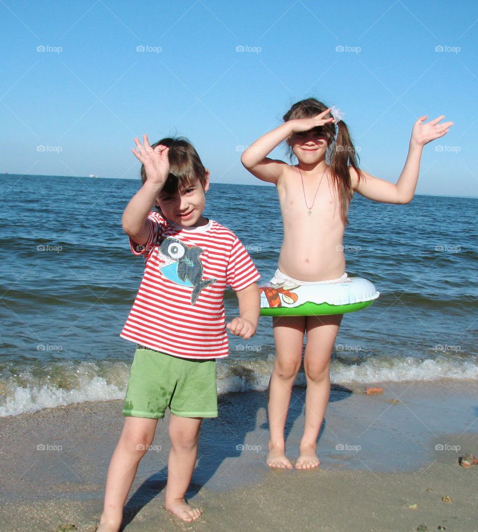 boy and girl stand on the beach near the sea