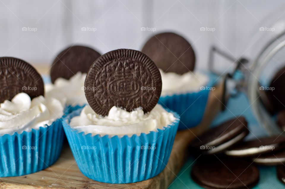 Oreo cookie ice cream cupcakes on a wooden board and white and blue background 