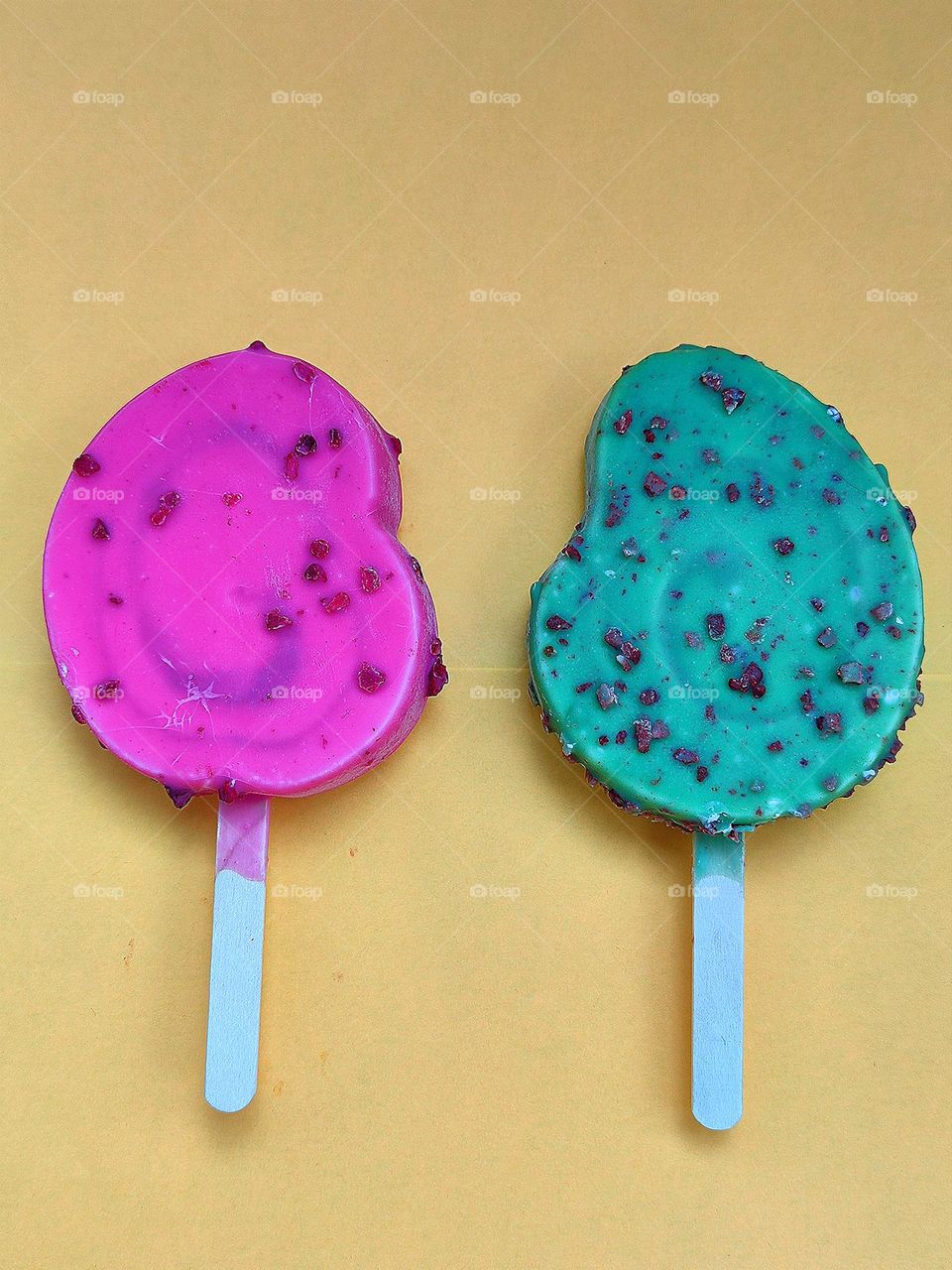 Summer. Time to cool off. On an orange background are two ice creams: red raspberry with raspberry pieces and green kiwi with chocolate pieces. Contrast of colors and taste