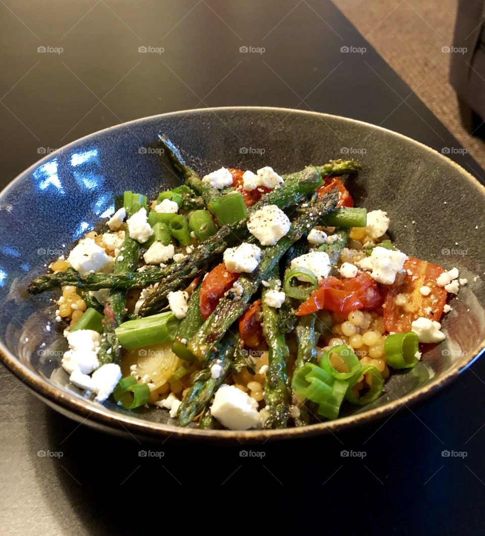 Mediterranean style couscous topped with green onion, asparagus, roasted heirloom tomato, and feta cheese. 