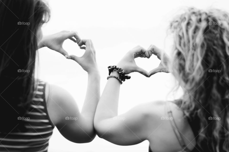 two friends making hearts. two girl friends making heart shapes with hands