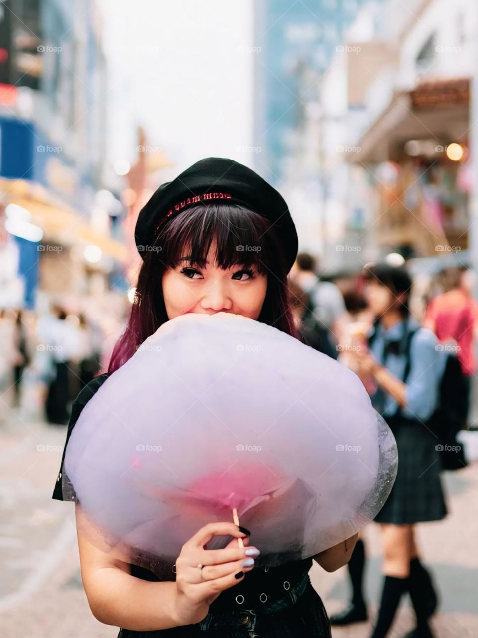 Portrait of girl holding cotton candy while standing on street in city