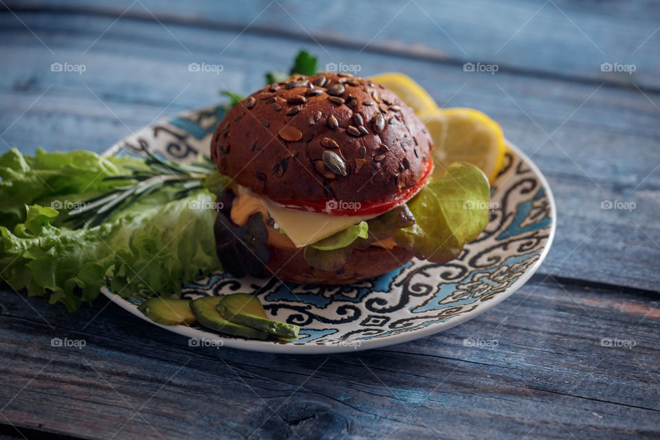 Dark burger with grain bread, cream cheese and avocado