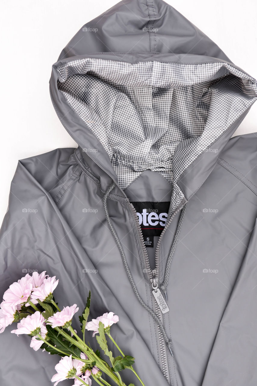 Flat lay of a gray raincoat with a pink bouquet of flowers