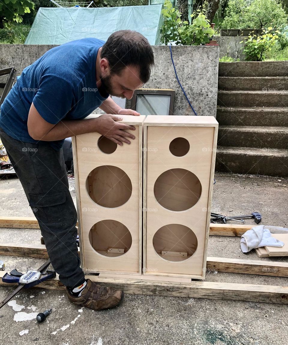 A man puts the final touches to a pair of speaker cabinets he has built