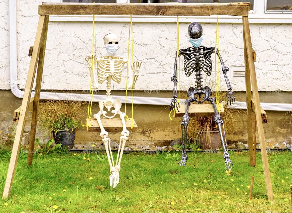 Scary skeletons with masks on swing at Halloween 