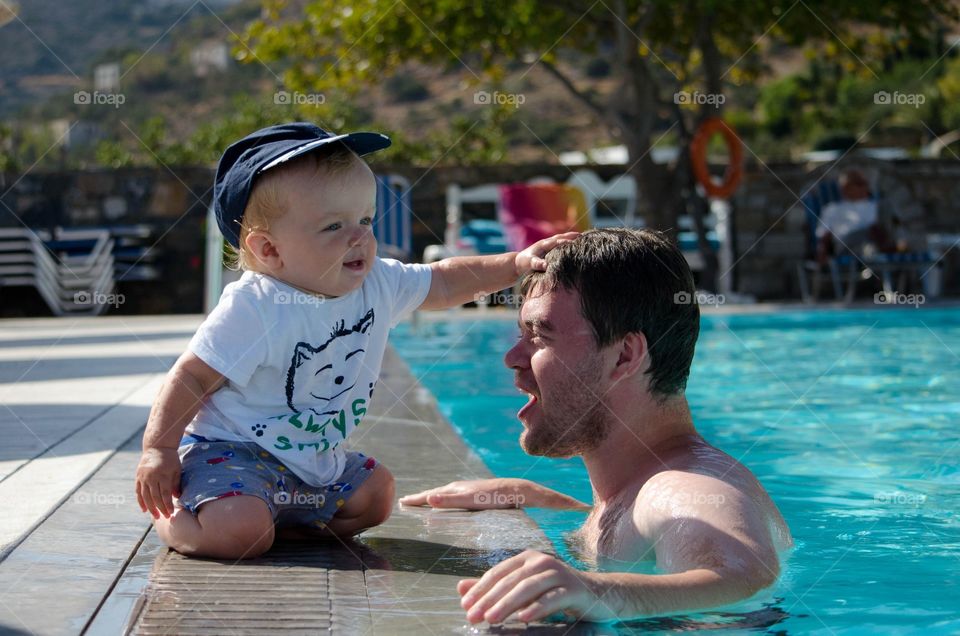 playing in swimming pool. father and son, happy family 