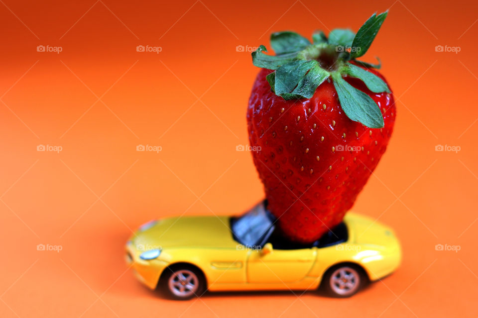 A strawberry in a toy car