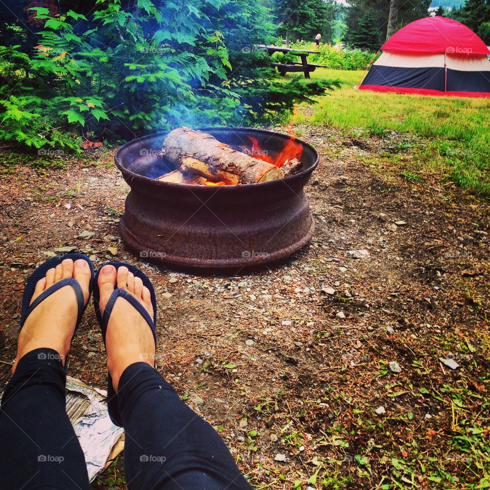Camping. Toasting toes by the fire. Tent life. Warm fire pit in the summer sun. 