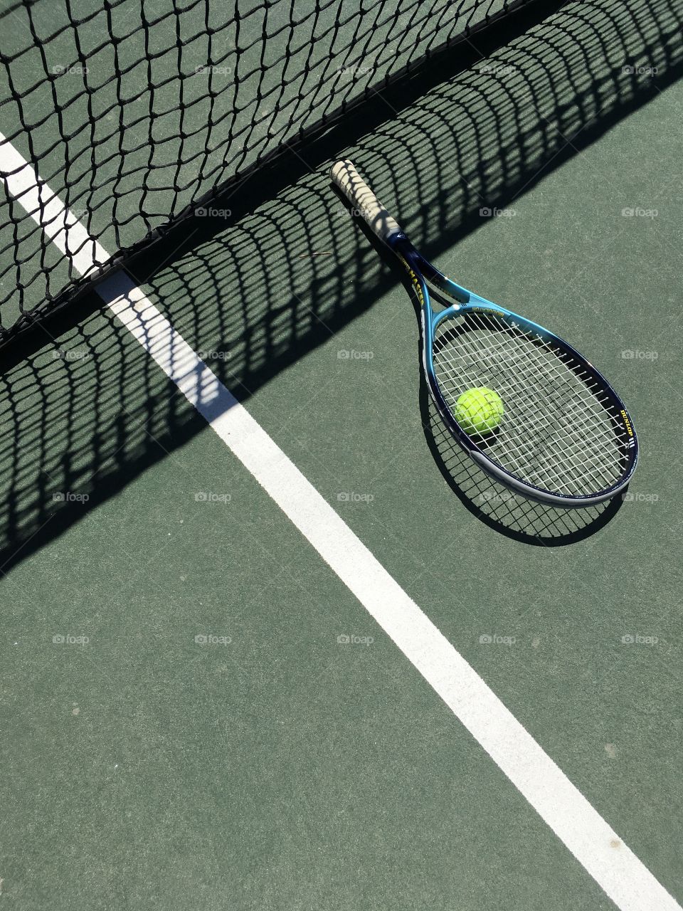 Tennis equipment illuminated on a court against shadows from the net 