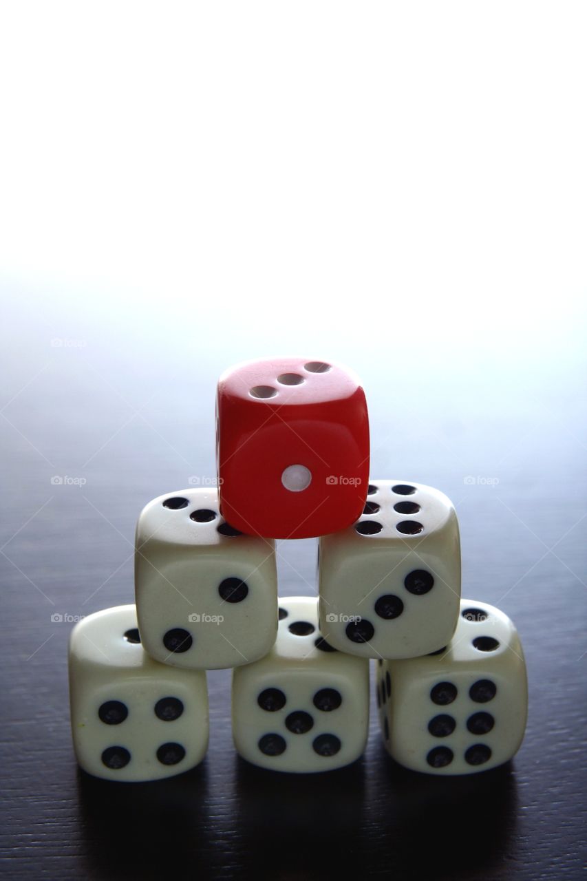 red and white game dice. 1 red game dice on top of stacked white game dice